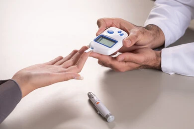 فحص دم منزلي لمرضى السكري، بورتريه مقرب ليد ممرض يرتدي اليونيفورم يقوم بفحص نسبة السكر في الدم لمريضة عربية خليجية إماراتية ترتدي العباءة، خدمات الرعاية الصحية المنزلية، متابعة طبية عاجلة، خلفية بنية.