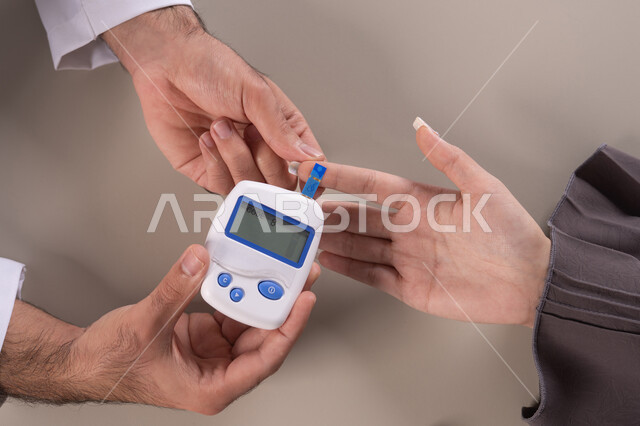 Blood sugar measuring device for patients, a close-up portrait of a nurse's hand wearing a uniform checking the blood sugar level of an Arab Gulf Emirati female patient wearing an abaya, home healthcare, quick follow-up for patients, brown background.