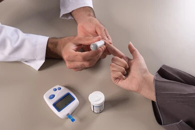 الرعاية الصحية والفحص الطبي السريع في البيت, جهاز قياس سكر الدم لمرضى السكري، بورتريه مقرب ليد ممرض يرتدي اليونيفورم يقوم بفحص نسبة السكر في الدم لمريضة عربية خليجيه اماراتية ترتدي العباءة ، شركات التمريض المنزلي، ، خلفية بنية