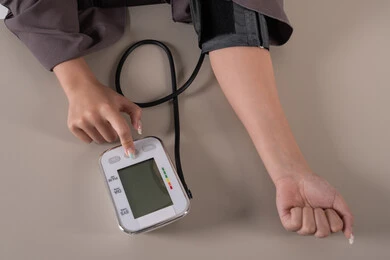 المتابعة الدورية لفحص الدم, العناية والاهتمام والحفاظ على الصحة, بورتريه مقرب ليد امراة عربية خليجية  اماراتية ترتدي العباءه تقوم بقياس ضغط الدم باستخدام الميزان الالكتروني, مفهوم الطب والرعاية الصحية, خلفية بنية