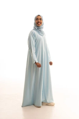 الاهتمام بالأناقة والمظهر الخارجي، مفهوم الأنوثة والنعومة والثقة بالنفس، بورتريه لامرأة عربية خليجية سعودية محجبة ترتدي عباءة تقف باستقامة تنظر الى شيء ما، صورة الجسم بالطول الكامل، خلفية بيضاء