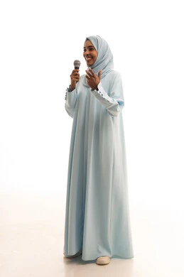 فن إلقاء الخطابات والندوات، التدريب الصوتي وتقديم البرامج الاذاعيه، بورتريه لشابة عربية خليجية سعودية ترتدي العباءة و الحجاب تمسك بيدها الميكروفون، ايماءات وتعابير وجه و يدين تعبر عن الغناء والطرب،الجسم بالطول الكامل، خلفية بيضاء