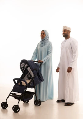 مفهوم الأسرة السعيدة المترابطة، عائلة عمانية تقضي وقت ممتع، مفهوم الأسرة السعيدة المترابطة، بورتريه لامراه عربيه خليجيه عمانية ترتدي العباءة و الحجاب تمسك عربة الطفل برفقة زوجها، أجواء أسرية مليئة بالمودة, الجسم بالطول الكامل، خلفية بيضاء