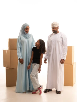 نقل العفش لبيت جديد من خلال العديد من الصناديق متعددة الأحجام ، بورترية  لعائلة عربية خليجية عمانية سعيدة داخل المنزل الجديد ، امتلاك بيت جديد ،ايماءات وجه تدل على السعادة والانسجام ، خلفية بيضاء