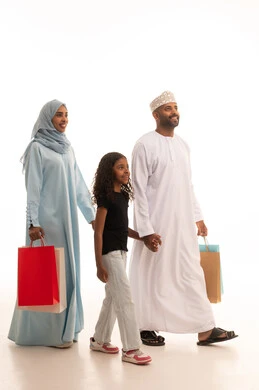Enjoying shopping and buying items during Black Friday, shopping for global products, a portrait of an Arab Gulf couple from Oman carrying colorful shopping bags with their daughter, taking advantage of discounts and seasonal offers, full body length, white background.