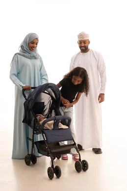 Caring for and raising children, the importance of parents and their essential role in the upbringing and development of their offspring, a portrait of an Omani Gulf Arab woman wearing an abaya and hijab standing with her husband and daughter pushing a stroller, going on family outings and trips, an Omani family enjoying pleasant times, full-body shot, white background.