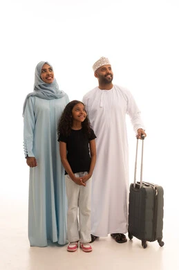 النظر للاعلى الى شيء ما بإيماءات السعادة والسرور، بورتريه لسيدة عربية خليجية عمانية ترتدي العباءة والحجاب تقف مع زوجها و ابنتها بجانب حقيبة الأمتعة، الإستعداد لقضاء الإجازة الصيفية والذهاب في رحلة سفر، الأجواء العائلية المليئة بالحب، الجسم بالطول الكامل، خلفية بيضاء