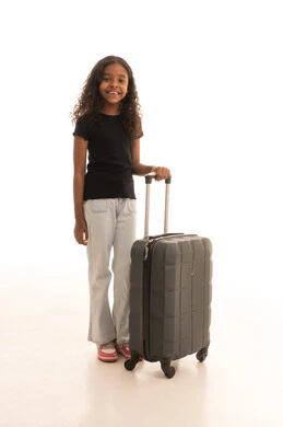 Looking at the camera with expressions of happiness and joy, preparing for travel and tourist trips, spending enjoyable times during the summer vacation, a smiling Arab Gulf Saudi girl wearing casual attire holding a travel bag, full body, white background.