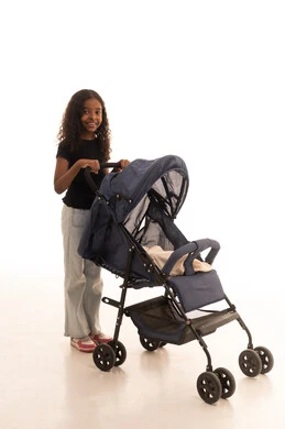 تقوية العلاقة الأخوية، قضاء أوقات عائلية ممتعة، مفهوم الأسرة السعيدة ، بورتريه لبنت عربية خليجية سعودية ترتدي الزي الكاجوال تمسك عربة الأطفال بإيماءات تدل على السعادة و المحبة، الجسم بالطول الكامل، خلفية بيضاء