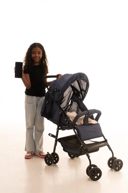 عرض شاشة سوداء عبر الجوال، قضاء أوقات عائلية ممتعة، مفهوم الأسرة السعيدة ، تقوية رابطة الأخوة، بورتريه لبنت عربية خليجية سعودية ترتدي الزي الكاجوال تمسك  عربة الأطفال بإيماءات تدل على السعادة و المحبة، الجسم بالطول الكامل، خلفية بيضاء