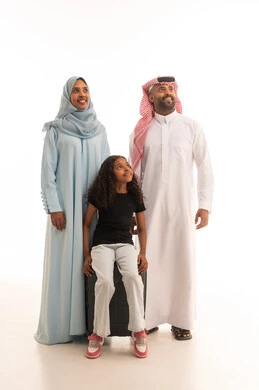 Looking at something, preparing for the summer vacation, a portrait of a smiling and happy Saudi Gulf Arab family ready to travel, a Saudi Gulf Arab girl wearing casual attire sitting on a suitcase, the concept of tourism and travel, full body, white background. Looking at something, preparing for the summer vacation, a portrait of a smiling and happy Saudi Gulf Arab family ready to travel, a Saudi Gulf Arab girl wearing casual attire sitting on a suitcase, the concept of tourism and travel, full body, white background.