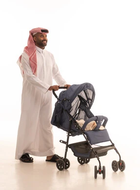 أهمية الأب ودوره الأساسي في تربية ونشأة الأبناء، مفهوم الأبوة والرعايه والاهتمام بالأولاد, بورتريه لأب عربي خليجي سعودي يرتدي الزي التقليدي و الشماغ  يقوم بجر عربة الأطفال بايماءات السعادة والسرور، القيام بالنزهات والجولات العائلية، خلفية بيضاء