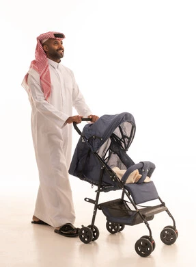The concept of fatherhood, care, and attention to children, the importance of the father and his essential role in raising and nurturing children, a portrait of an Arab Gulf Saudi father wearing traditional attire and a ghutrah, pulling a stroller with gestures of happiness and joy, going on family outings and tours, white background.