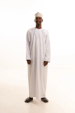 Attention to appearance and elegance, the concept of masculinity and self-confidence, a portrait of a young Arab Gulf Omani man with a dark complexion wearing a dishdasha and kumma, looking with expressions of joy, standing upright and steady, full-body image, white background.