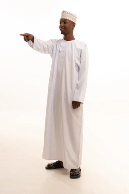 الإشارة والتوجيه إلى مكان ما، شد الإنتباه ولفت النظر،بورتريه لشاب عربي خليجي عماني اسمر يرتدي الدشداشة والكمة يشير بإصبع السبابة إلى شيء ما ينظر بإيماءات السعادة والثقة بالنفس، تحديد موقع أو هدف معين، الجسم بالطول الكامل، خلفية بيضاء