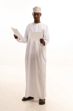 بورتريه لشاب عربي خليجي عماني اسمر يرتدي الدشداشة والكمة  يحمل بيده مجموعة من الاوراق البيضاء، مراجعة ومتابعة الخطط والمشاريع المكتبية بإيماءات التركيز، اعداد التقارير الخاصة بالعمل، التدقيق في قراءة الملاحظات، خلفية بيضاء