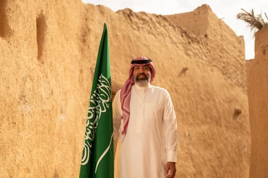 إيماءات الفخر و السرور بالانتماء للوطن, رجل عربي خليجي سعودي مبتسم يرتدي الشماغ و الثوب التقليدي يقف في بيت طيني ويحمل بيده علم المملكة، يوم بدينا 1727 م، فن العمارة القديم وبناء البيوت الطينية، يوم العلم 11 مارس، إحياء ذكرى اليوم الوطني السعودي 23 سبتمبر إيماءات الفخر و السرور بالانتماء للوطن, رجل عربي خليجي سعودي مبتسم يرتدي الشماغ و الثوب التقليدي يقف في بيت طيني ويحمل بيده علم المملكة، يوم بدينا 1727 م، فن العمارة القديم وبناء البيوت الطينية، يوم العلم 11 مارس، إحياء ذكرى اليوم الوطني السعودي 23 سبتمبر