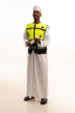 الإعمار بسواعد أبناء الوطن، مفهوم الهندسة والانشاءات المعمارية، الاحتراف فى التخطيط، المتابعة والإشراف على العمل بشكل مباشر،بورتريه لمهندس عربي خليجي عماني اسمر يرتدي الدشداشة والكمة والسترة الخاصة وخوذة الحماية يقف وبيده مخطط هندسي ، الجسم بالطول الكامل، خلفية بيضاء