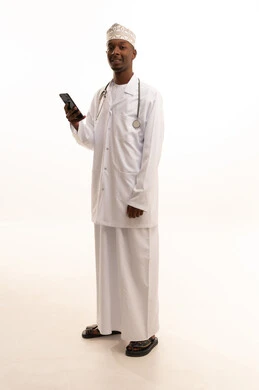 Providing services to patients with efficiency, making a phone call, using technology in research and development, conducting remote medical consultations, a portrait of a young Arab Gulf Omani man with a dark complexion wearing a dishdasha and kumma with a white coat using a mobile phone, health professions and jobs, white background.