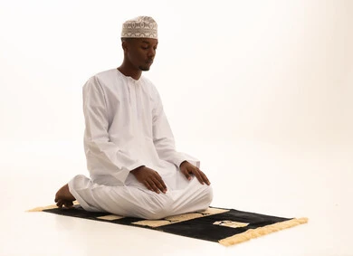 الركوع والسجود والخشوع لله، بورتريه لشاب عربي عماني خليجي اسمر يرتدي الدشداشة والكمة يقف على السجادة و يؤدي فريضة الصلاة ، آداء صلاة التراويح ، الدعاء والتضرع الى الله، أذكار وأدعية وفرائض، خلفية بيضاء.