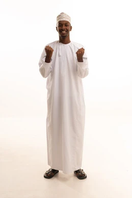 الاندماج بتشجيع فريق كرة القدم, إيماءات الفوز والانتصار,بورتريه لشاب عربي خليجي عماني اسمر يرتدي الدشداشة والكمة  يرفع يديه بتعابير التفاعل والحماس, خلفية بيضاء