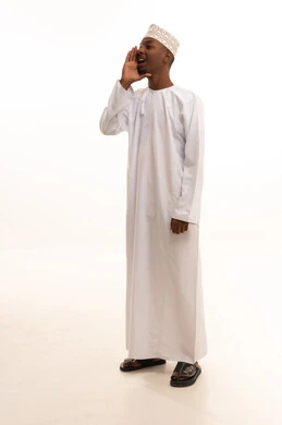 وضع اليد بجانب الفم لزيادة حدة الأصوات،النداء بصوت مرتفع,بورتريه لشاب عربي خليجي عماني اسمر يرتدي الدشداشة والكمة  ينظر إلى الكاميرا بإيماءات المناداة لشخص ما، الصراخ والتكلم بنبرة عالية للسماع بشكل جيد، محادثات وتواصل اجتماعي، خلفية بيضاء