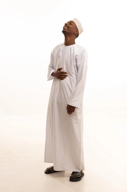 بورتريه لشاب عربي خليجي عماني اسمر يرتدي الدشداشة والكمة  ينظر الى الكاميرا بتعابير الضحك الهستيري,ايماءات البهجة والسرور الشديد، الشعور بالفرح والسعادة،  خلفية بيضاء