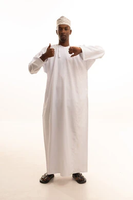 الحيرة والتردد بخصوص امر ما،بورتريه لشاب عربي خليجي عماني اسمر يرتدي الدشداشة والكمة يرفع اصبع الابهام للاعلى والاسفل بإيماءات عدم الموافقه والموافقه، عدم الإعجاب والإعجاب، مفهوم الرفض والقبول، خلفية بيضاء