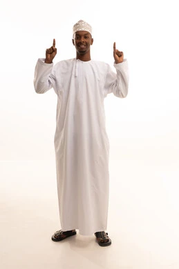Pointing and directing to a place, attracting attention and drawing notice, a portrait of a young Arab Gulf Saudi man with a dark complexion wearing a white thobe, pointing with his index finger to something, looking with gestures of happiness and self-confidence, identifying a specific location or goal, full-body, white background.