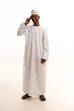 تعابير الوجه ولغة الجسد المختلفة, مفهوم السلام والترحيب,بورتريه لشاب عربي خليجي عماني اسمر  يرتدي الدشداشة والكمة  يرفع اليد اليمني لإلقاء التحية, ايماءات السرور والسعادة, صورة الجسم بالطول الكامل، خلفية بيضاء