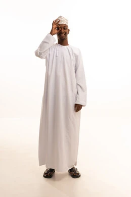 إشارات التركيز على شيء ما، البحث والاستطلاع بأمر معين، الشعور بالسعادة لإكتشاف الحقائق،بورتريه لشاب عربي خليجي عماني اسمر يرتدي الدشداشة والكمة  يضع يده على عينه للتدقيق والنظر الى شيء محدد، خلفية بيضاء