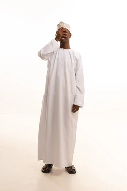 Vision strength test and examination, the concept of vision assessment, a portrait of a young Arab Gulf Omani man with a dark complexion wearing a dishdasha and kumma, placing his hand over his eye, gestures for eye examination, white background.