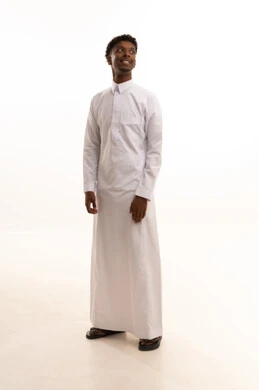 Attention to appearance and elegance, the concept of masculinity and self-confidence, a portrait of a young Arab Gulf Saudi man with a dark complexion wearing a white thobe, looking with expressions of joy, standing upright and steady, full-body image, white background.