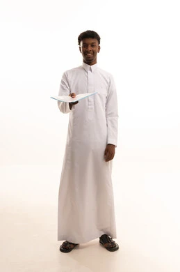 التدقيق في قراءة الملاحظات، اعداد التقارير الخاصة بالعمل، بورتريه لشاب عربي خليجي سعودي اسمر يرتدي الثوب الابيض يحمل بيده مجموعة من الاوراق البيضاء، مراجعة ومتابعة الخطط والمشاريع المكتبية بإيماءات التركيز، خلفية بيضاء