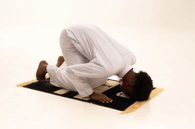 الدعاء والتضرع الى الله،  الركوع والسجود والخشوع لله، بورتريه لشاب عربي سعودي خليجي اسمر يرتدي الثوب التقليدي يقف على السجادة و يؤدي فريضة الصلاة ، آداء صلاة التراويح ، أذكار وأدعية وفرائض، خلفية بيضاء.