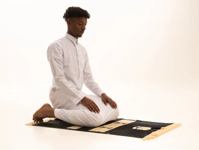 Remembrances, supplications, and obligations, bowing, prostration, and humility before God, a portrait of a young Arab Saudi Gulf man with a dark complexion wearing traditional attire standing on a prayer rug performing the prayer obligation, performing Taraweeh prayer, supplication and pleading to God, white background.