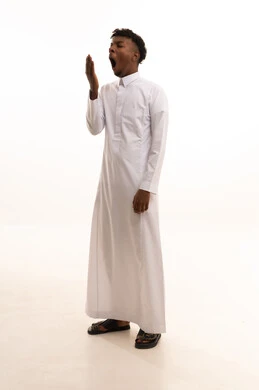 تعابير النعاس والحاجه الى النوم، بورتريه لشاب عربي خليجي سعودي اسمر يرتدي الثوب الأبيض يرفع يديه بإيماءات النعاس, الإحساس بالتعب والتثاؤب ,مفهوم الكسل والخمول، خلفيه بيضاء