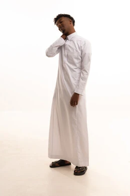 Neck, bone, and spine pain, gestures of distress and suffering, a portrait of a young Arab Gulf Saudi man with a dark complexion wearing a white thobe, holding his neck with gestures of pain, the necessity to see a doctor and receive treatment, white background.