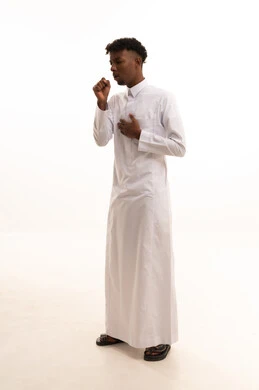 إيماءات الإرهاق والتعب الشديد، الإصابة بالأنفلونزا ونزلات البرد, الكحة والتهاب الحلق والحاجة للعلاج،  بورتريه لشاب عربي خليجي سعودي اسمر يرتدي الثوب الأبيض يضع يده أمام فمه ويقوم بالسعال, خلفية بيضاء