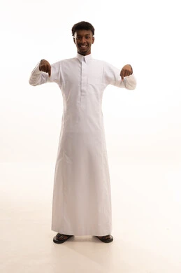 تحديد موقع أو هدف معين، الإشارة والتوجيه إلى مكان ما، شد الإنتباه ولفت النظر، بورتريه لشاب عربي خليجي سعودي اسمر يرتدي الثوب الابيض يشير بإصبعي السبابة إلى شيء ما ينظر بإيماءات السعادة والثقة بالنفس، الجسم بالطول الكامل، خلفية بيضاء