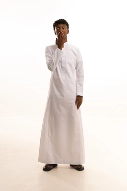 الهدوء والسكون وعدم الإزعاج، التوقف عن الكلام وخفض الصوت،بورتريه لشاب عربي خليجي سعودي اسمر يرتدي الثوب الابيض يضع أصبع السبابة على فمه بإيماءات طلب السكوت والصمت،خلفية بيضاء