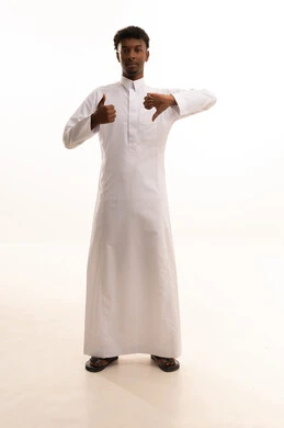 الحيرة والتردد بخصوص امر ما، بورتريه لشاب عربي خليجي سعودي اسمر يرتدي الثوب الأبيض  يرفع اصبع الابهام للاعلى والاسفل بإيماءات عدم الموافقه والموافقه، عدم الإعجاب والإعجاب، مفهوم الرفض والقبول، خلفية بيضاء