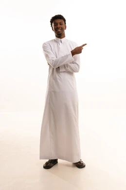It grabs attention and draws the eye, signaling and directing to a certain place, a portrait of a young Arab Gulf Saudi man with a dark complexion wearing a white thobe, pointing with his index finger to something, looking with gestures of happiness and self-confidence, identifying a specific location or goal, full-body, white background.