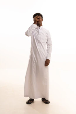 بورتريه لشاب عربي خليجي سعودي اسمر يرتدي الثوب الأبيض يضع يده على عينه ، ايماءات فحص العينين ، اختبار وفحص قوة النظر، مفهوم تقييم الرؤية ، خلفية بيضاء