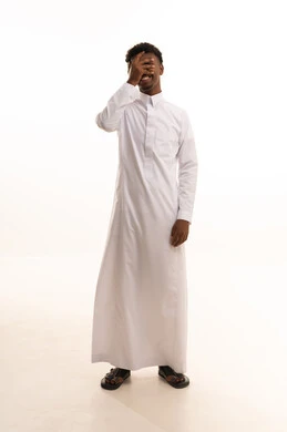 Eye strength test and examination, the concept of vision assessment, a portrait of a young Arab Gulf Saudi man with a dark complexion wearing a white thobe, placing his hand over his eye, gestures for eye examination, white background.