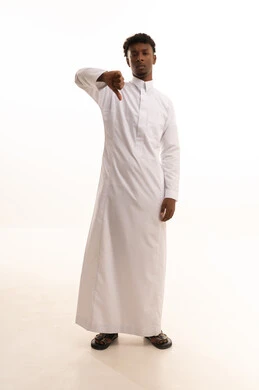 The thumb pointing down is a sign of rejection, hand movements and gestures of disapproval and agreement, a portrait of a young Arab Gulf Saudi man with a dark complexion wearing a white thobe indicating gestures of disapproval, white background. The thumb pointing down is a sign of rejection, hand movements and gestures of disapproval and agreement, a portrait of a young Arab Gulf Saudi man with a dark complexion wearing a white thobe indicating gestures of disapproval, white background.