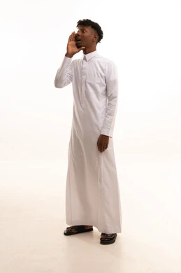 وضع اليد بجانب الفم لزيادة حدة الأصوات،النداء بصوت مرتفع, بورتريه لشاب عربي خليجي سعودي اسمر يرتدي الثوب الأبيض ينظر جانباً بإيماءات المناداة لشخص ما، الصراخ والتكلم بنبرة عالية للسماع بشكل جيد، محادثات وتواصل اجتماعي، خلفية بيضاء