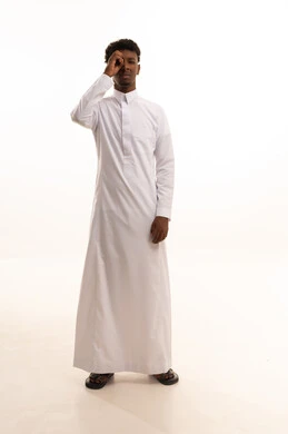 الشعور بالسعادة لإكتشاف الحقائق، إشارات التركيز على شيء ما، البحث والاستطلاع بأمر معين،بورتريه لشاب عربي خليجي سعودي اسمر يرتدي الثوب الأبيض يضع يده على عينه للتدقيق والنظر الى شيء محدد، خلفية بيضاء