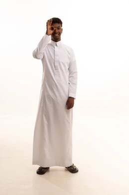 البحث والاستطلاع بأمر معين، إشارات التركيز على شيء ما،الشعور بالسعادة لإكتشاف الحقائق،بورتريه لشاب عربي خليجي سعودي اسمر يرتدي الثوب الأبيض يضع يده على عينه للتدقيق والنظر الى شيء محدد، خلفية بيضاء