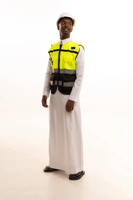Working in the engineering sector, the concept of engineering and architectural constructions, a portrait of a smiling Saudi Arabian Gulf engineer with a dark complexion wearing traditional attire, a helmet, and a safety vest, looking with gestures of joy, Saudi professions and jobs, construction by the hands of the nation's sons, white background.